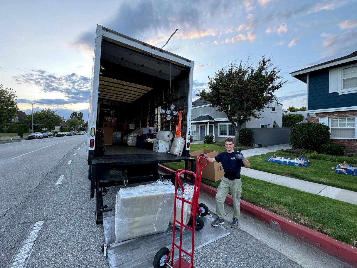 Mover standing beside a truck liftgate during an evening residential unload